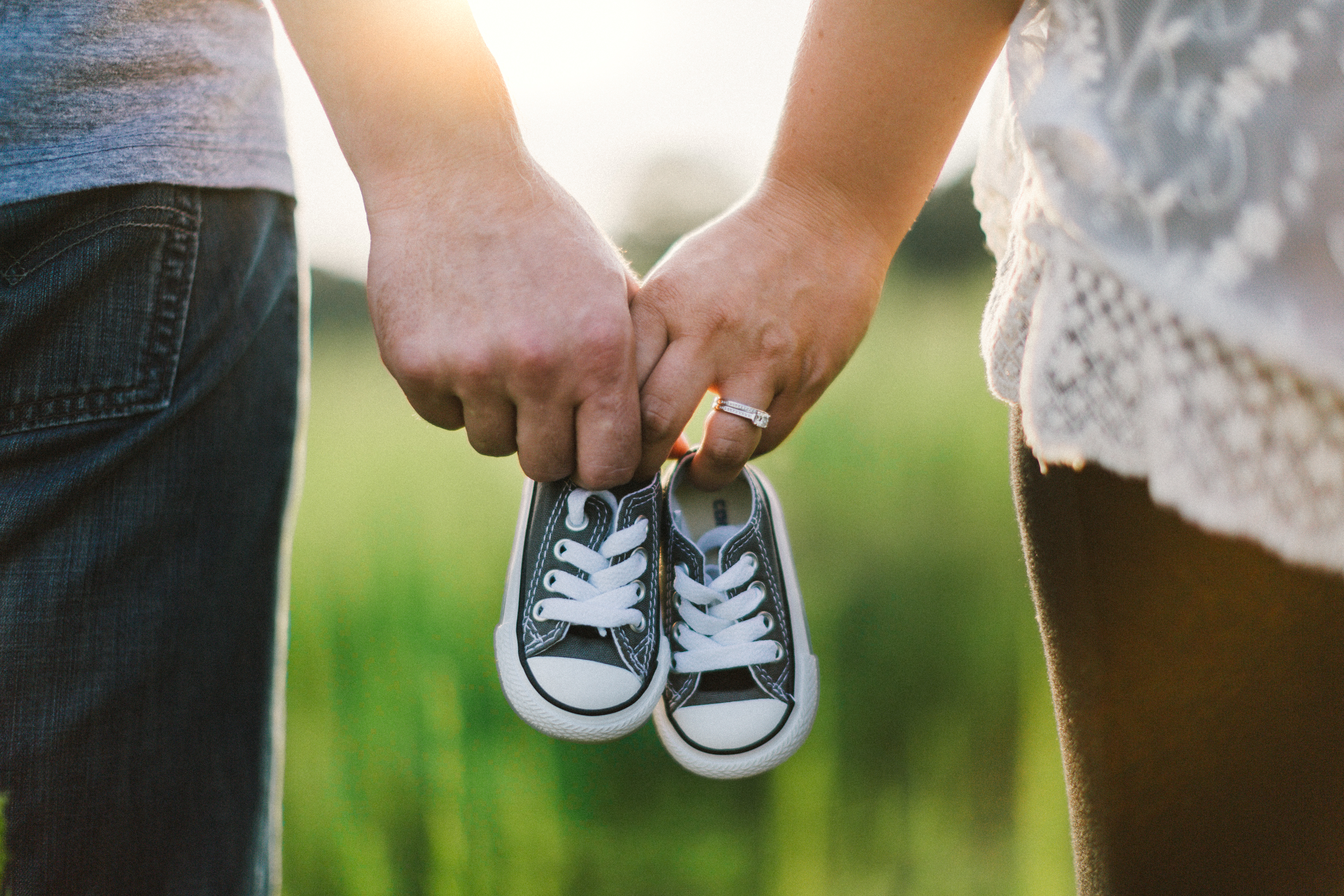 A couple holding hands whilst also holding a very small pair of trainers