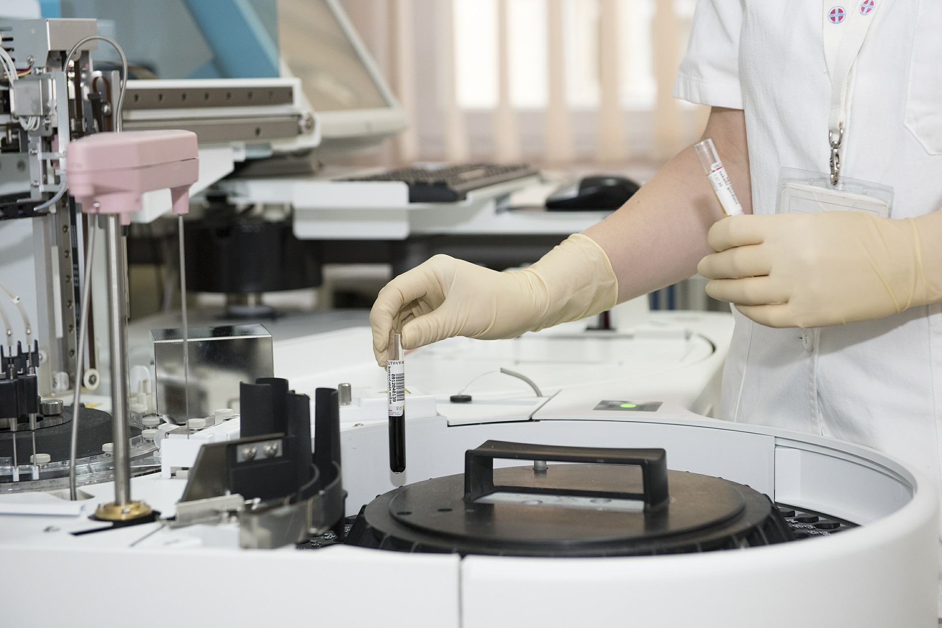 A lab assistant places test tubes containing liquid into a centrifuge