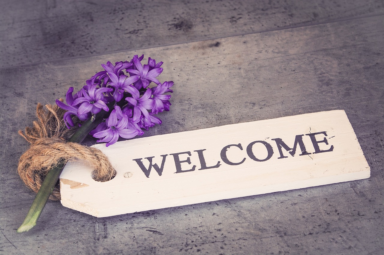 A purple flower with a ornate tag on it that reads 'welcome'