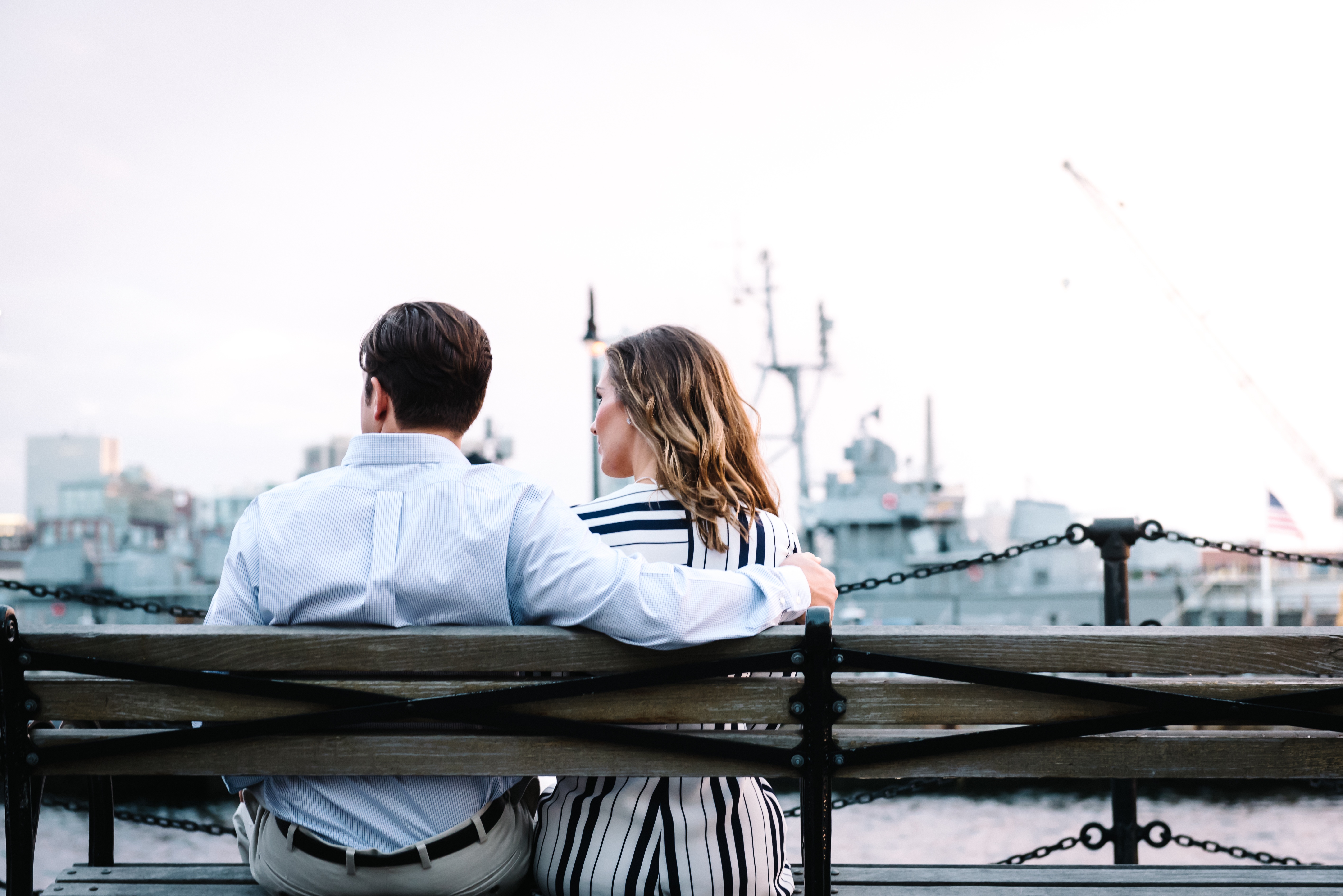 Two people sat by a harbour on a bench