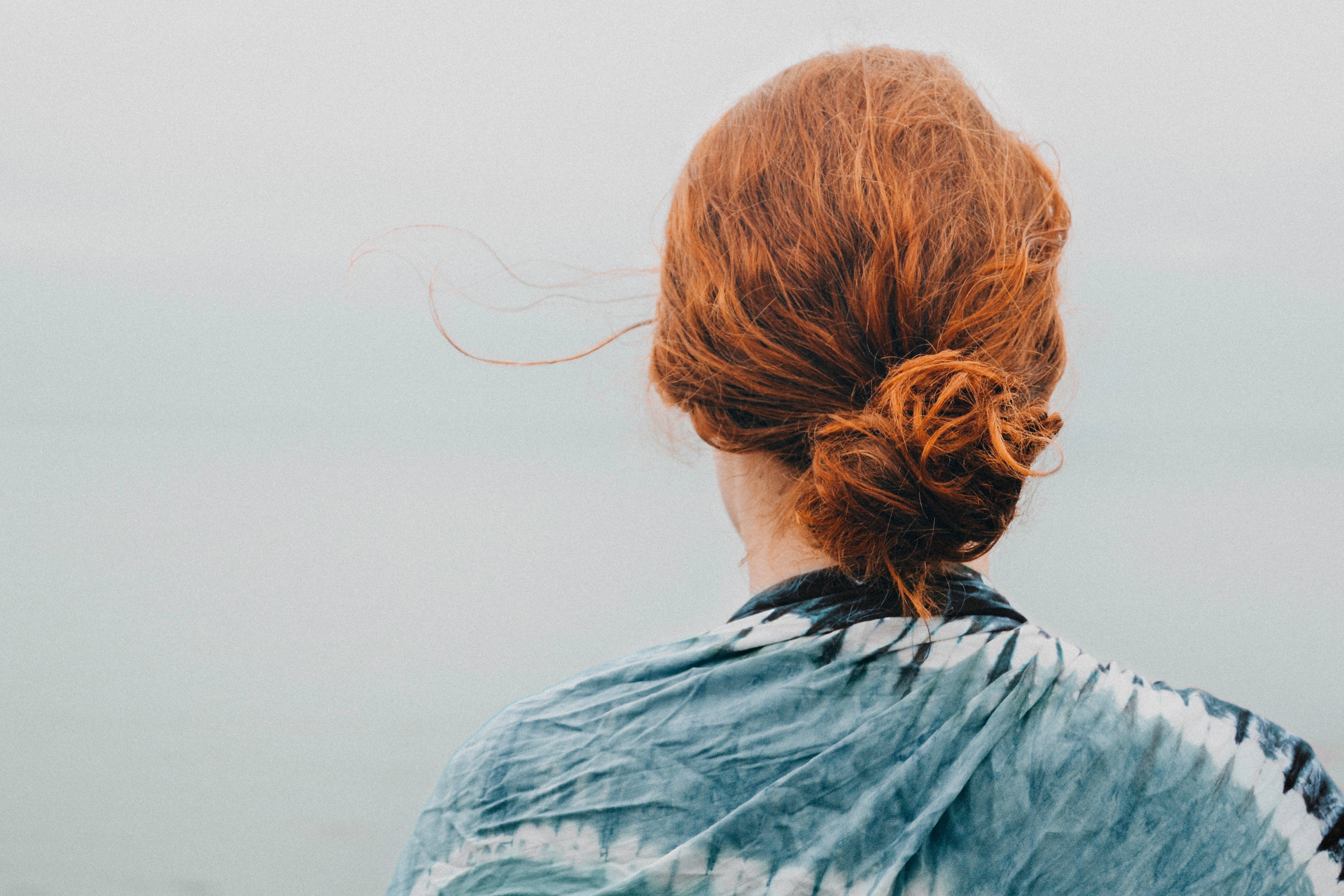 A woman with red hair looks out over a misty vista