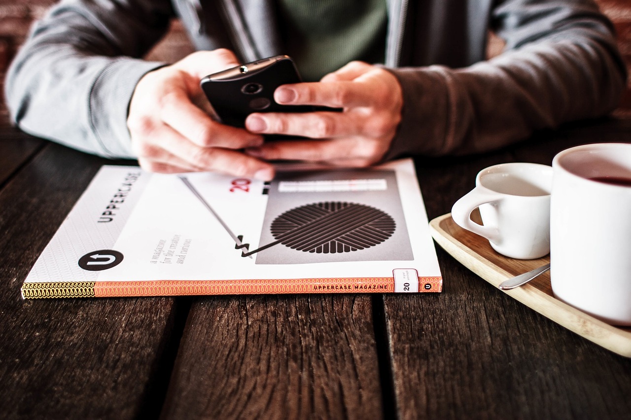 A person writes a message on their phone next to a closed book