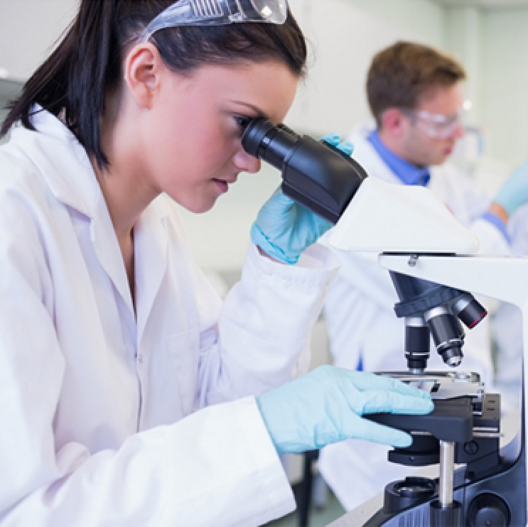 Scientist in a lab coat looking through the eyepiece of a microscope