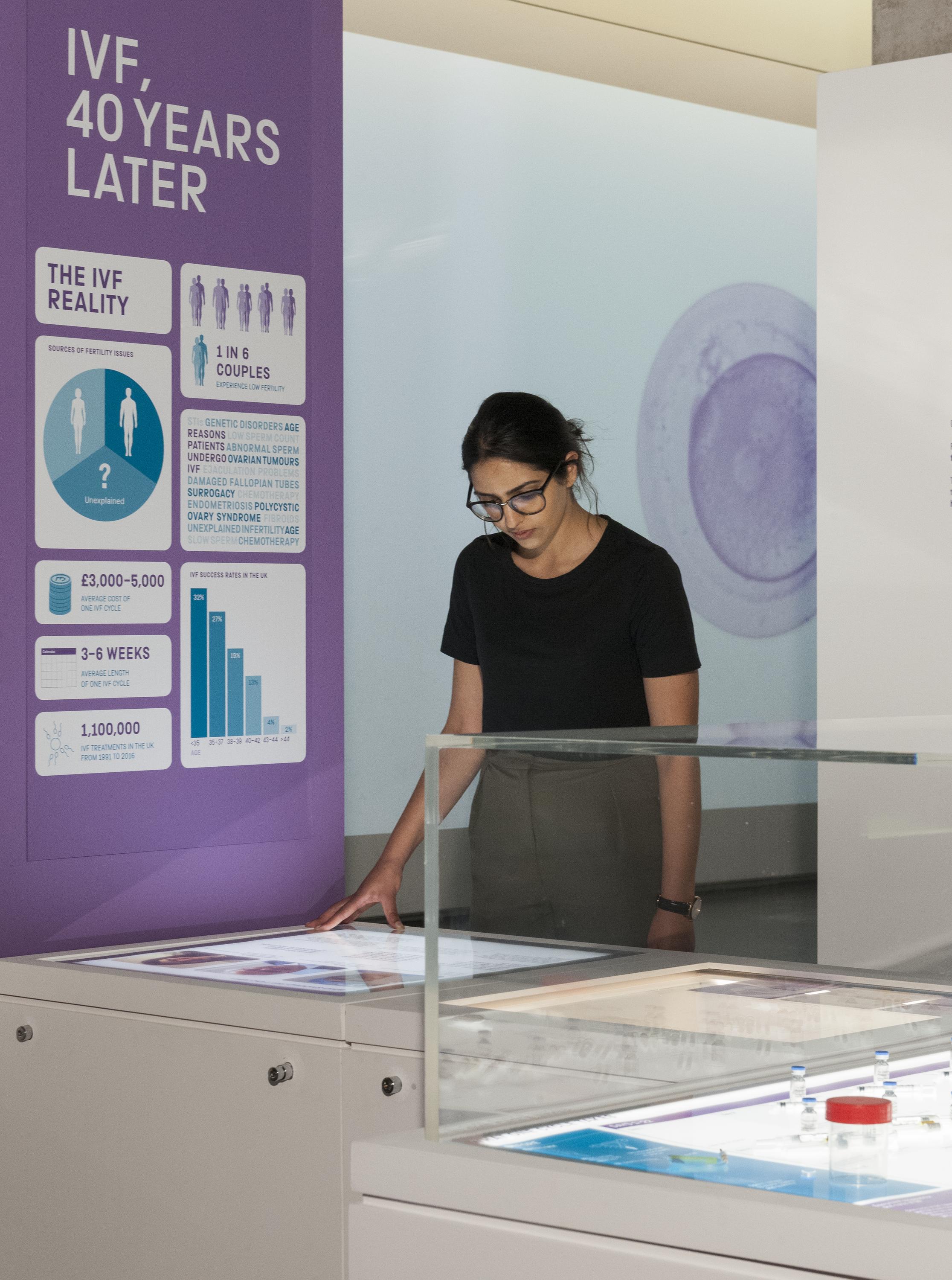 A woman looks at an interactive display at the Science Museum's latest exhibition on the history of IVF